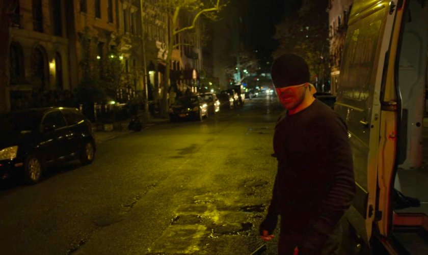 The Man in Black standing on a dark street outside van.