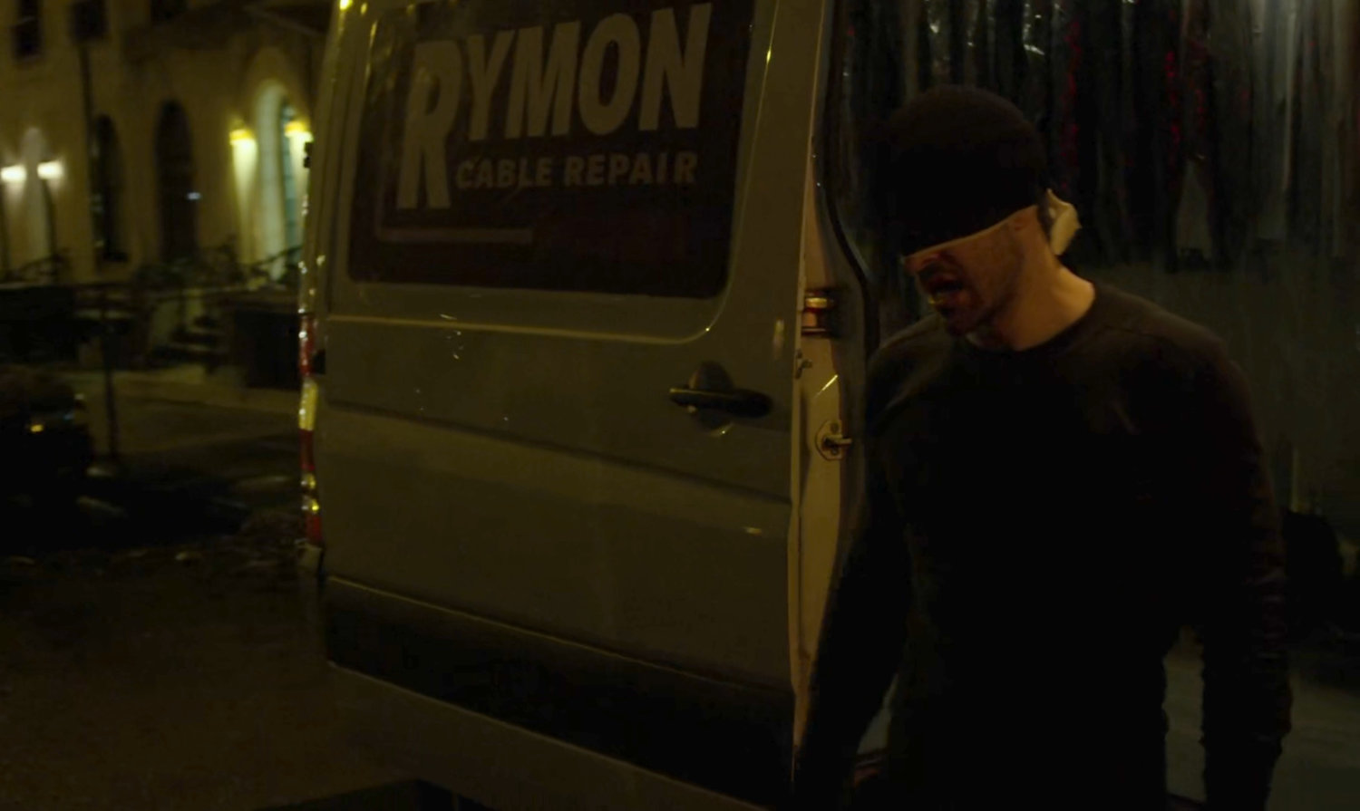 The Man in Black standing on a dark street outside van.