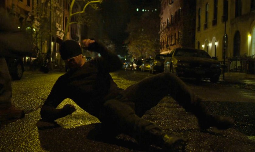 The Man in Black lying on a dark street outside van.