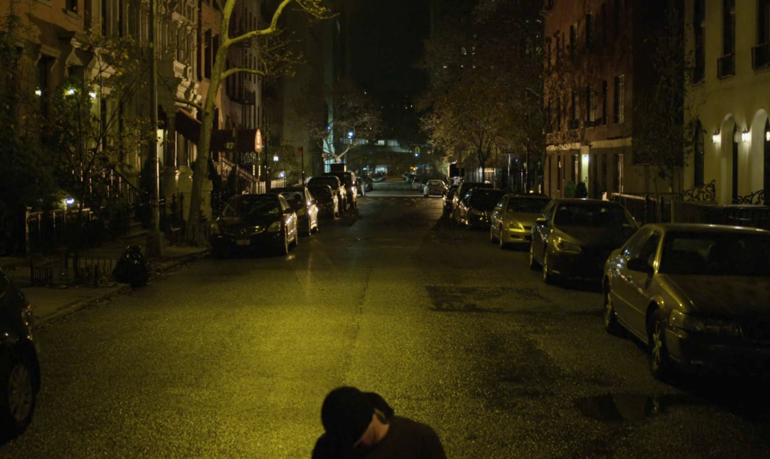 The Man in Black lying on a dark street outside van.