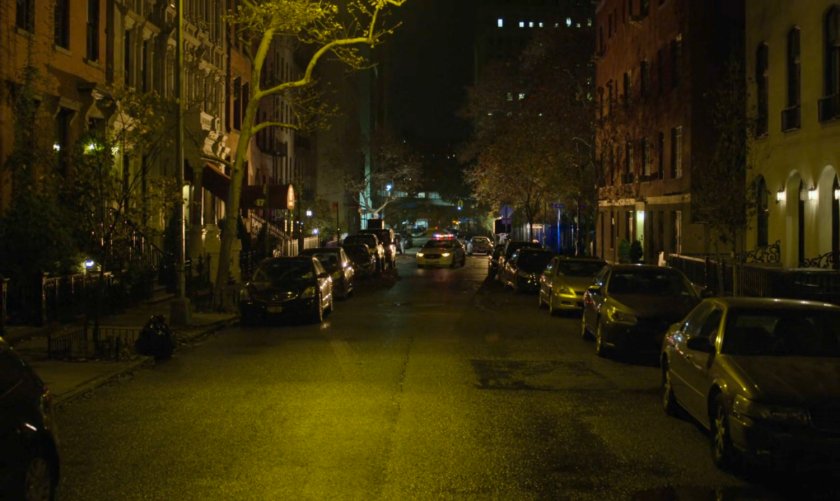 A police car enters a dark street.
