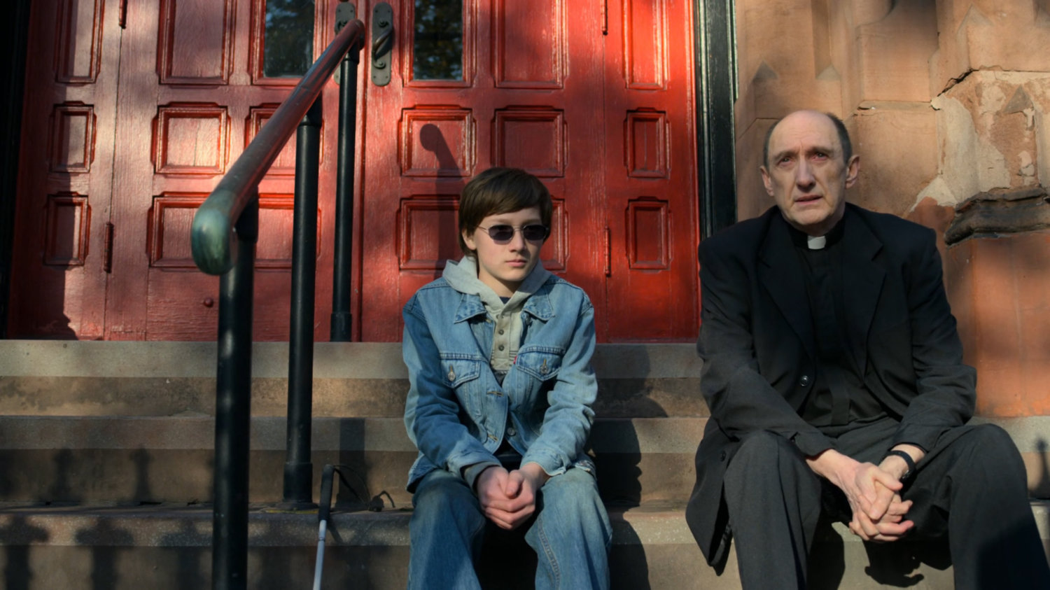 Young Matt speaks with Father Lantom outside the church.