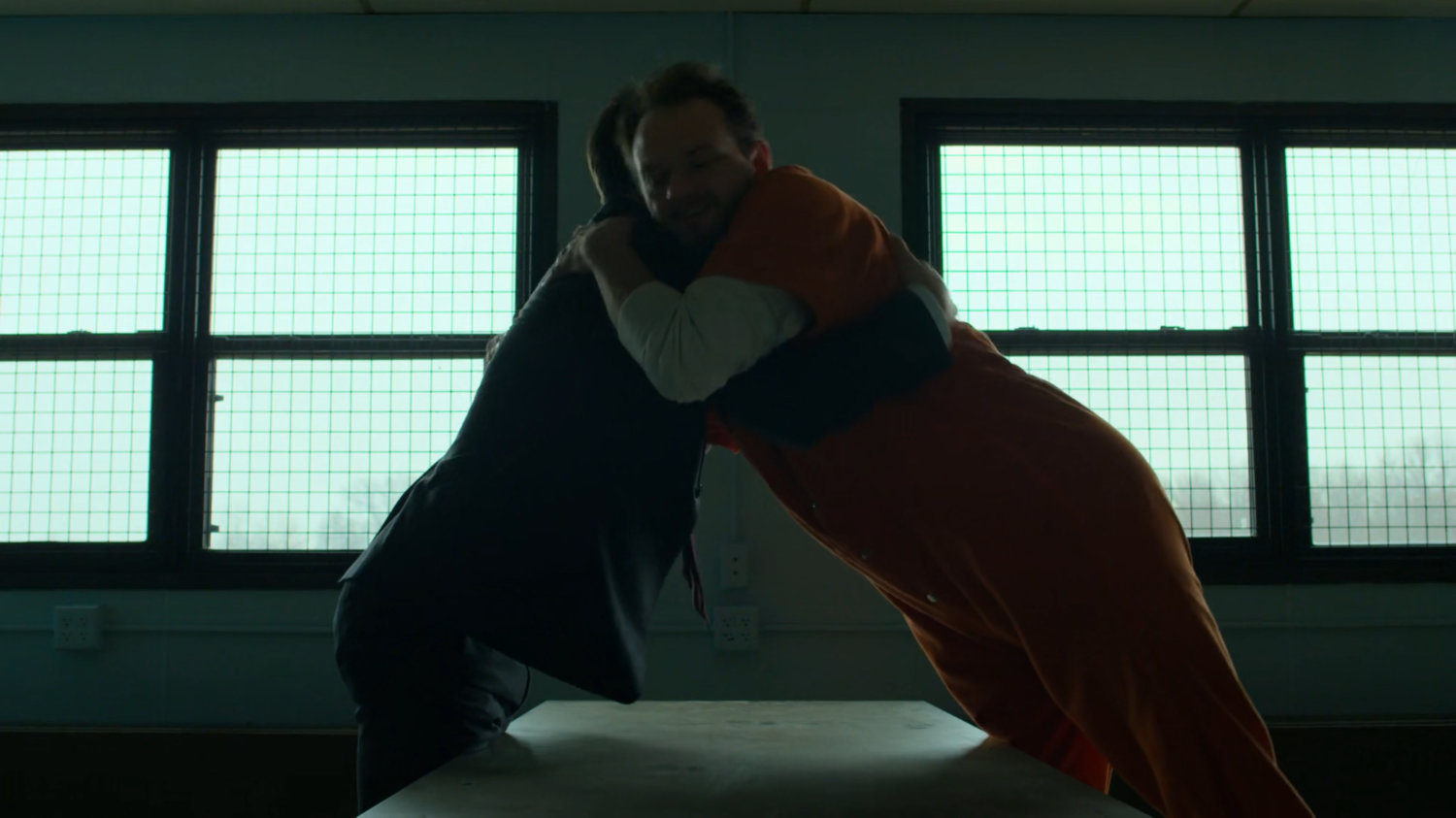 Matt and Michael hug in the penitentiary visitor room.