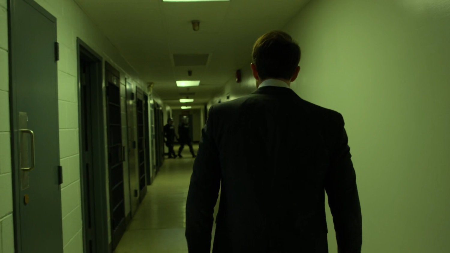 Matt walks towards guards in penitentiary hallway.