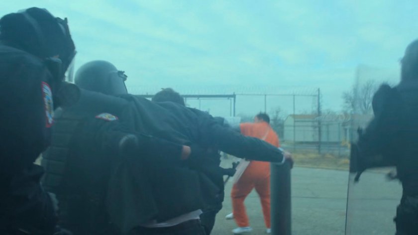 Guards lead Matt out of smokey entrance of penitentiary.
