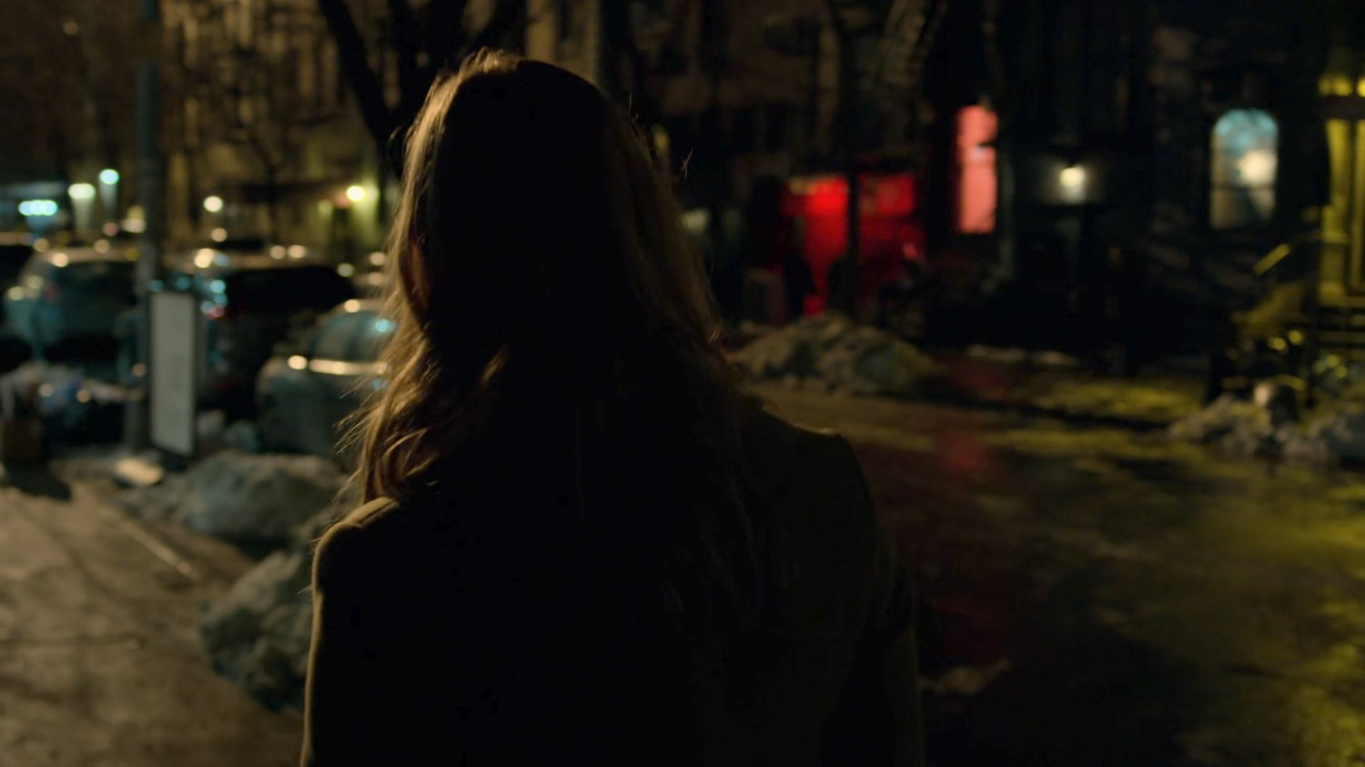 Karen walks along a dark sidewalk at night.