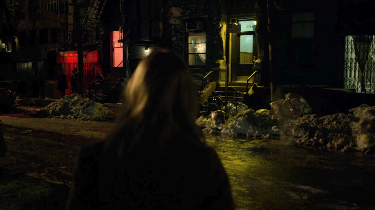 Karen crosses a dark street at night.