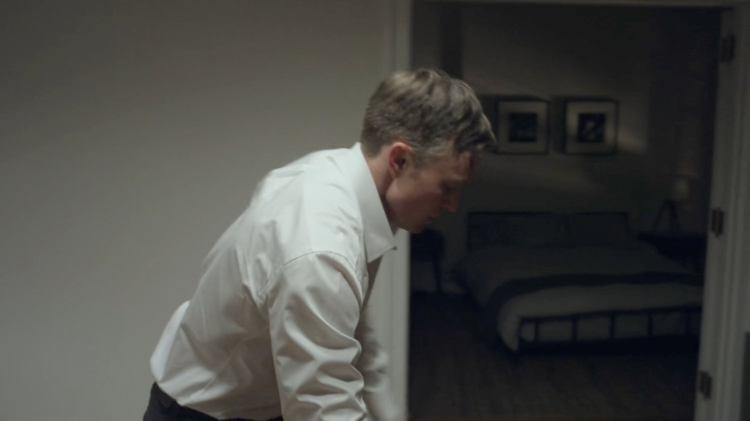 Dex leaning over the table in his apartment.