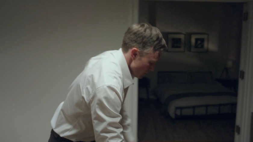 Dex leaning over the table in his apartment.