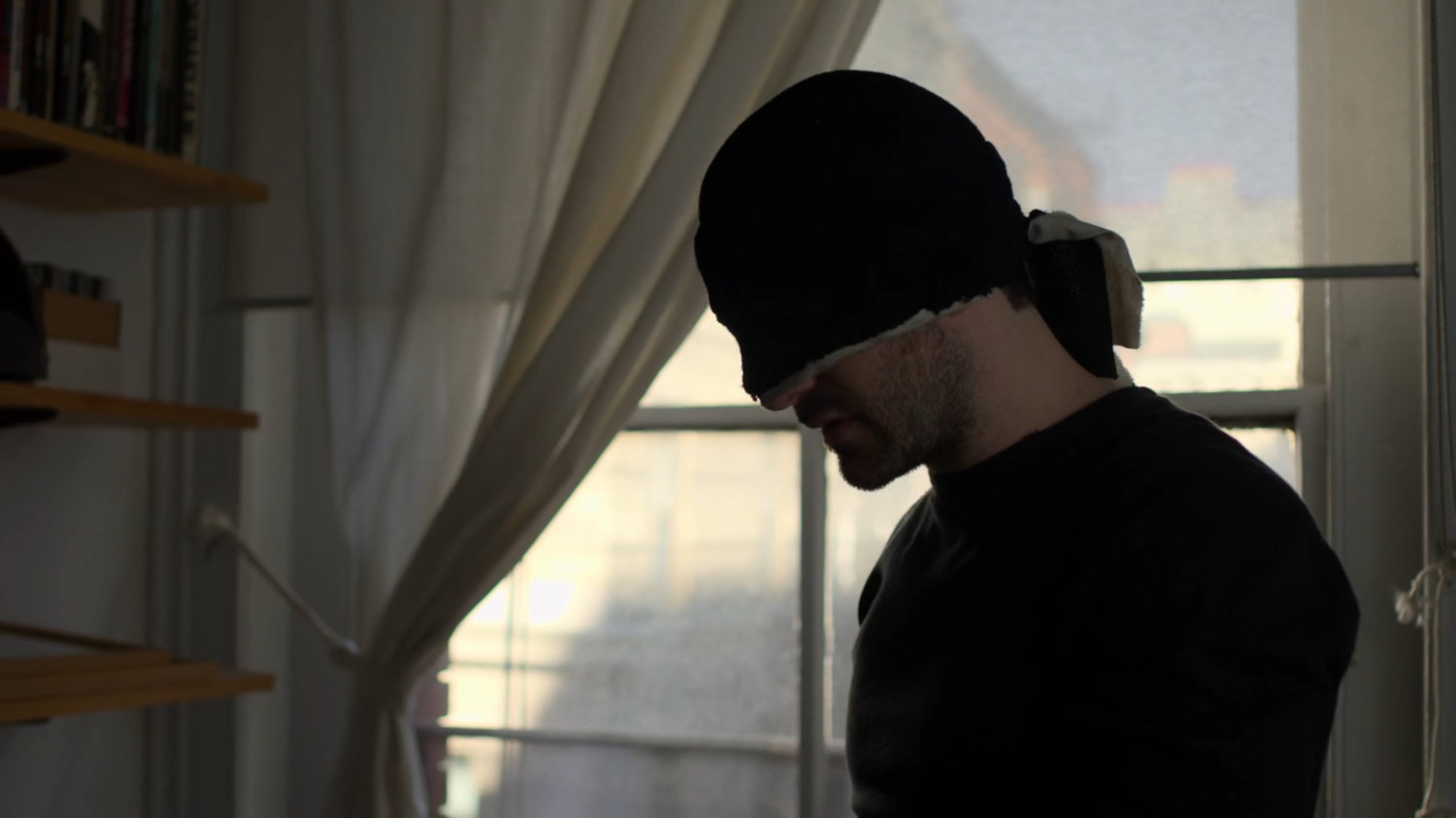 Matt standing by window in Karen's apartment.