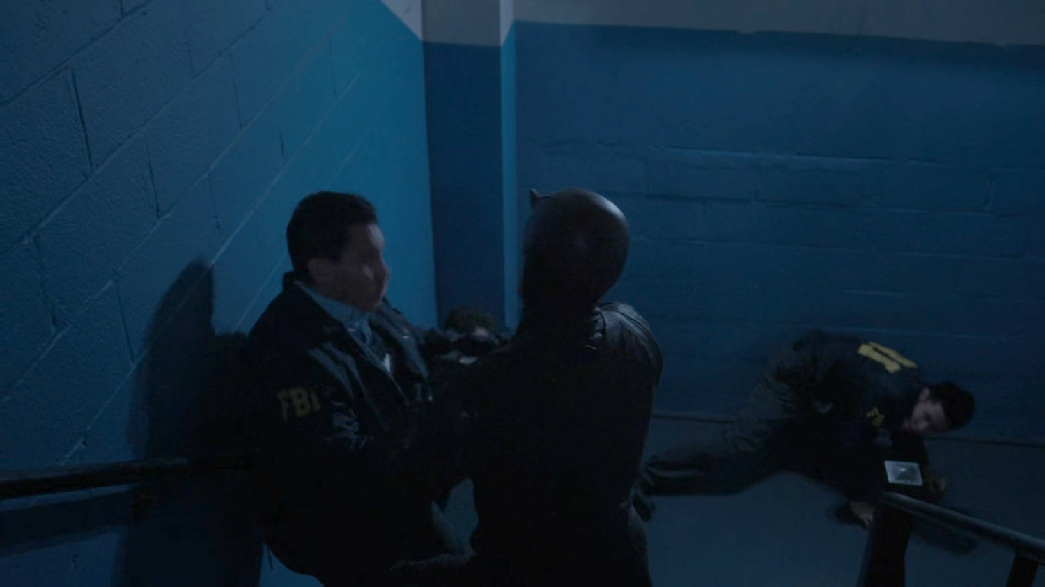 Dex, dressed as Daredevil, fight FBI agents in the stairwell.
