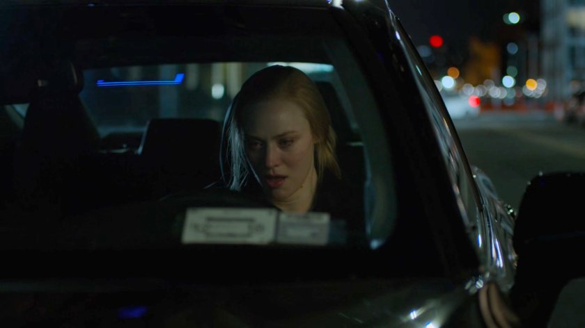 Karen sitting in her car on a street at night.