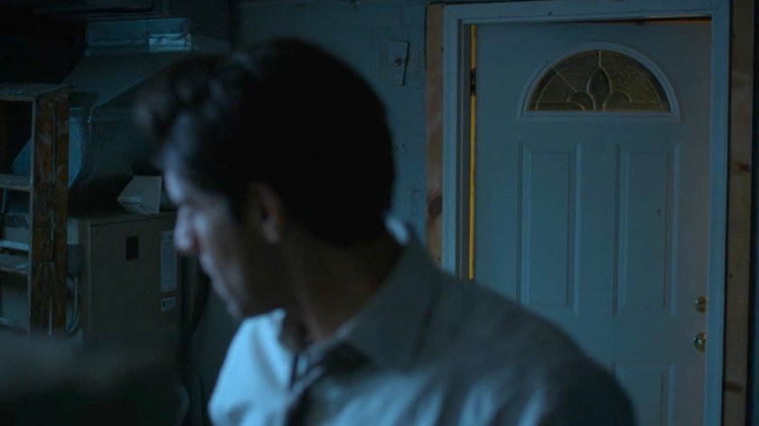 Ray in his basement looking over his shoulder at open door.