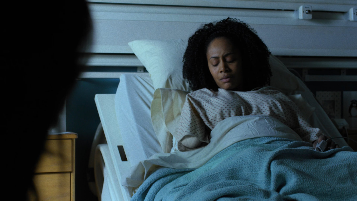 Misty in a hospital bed looking at her missing arm.
