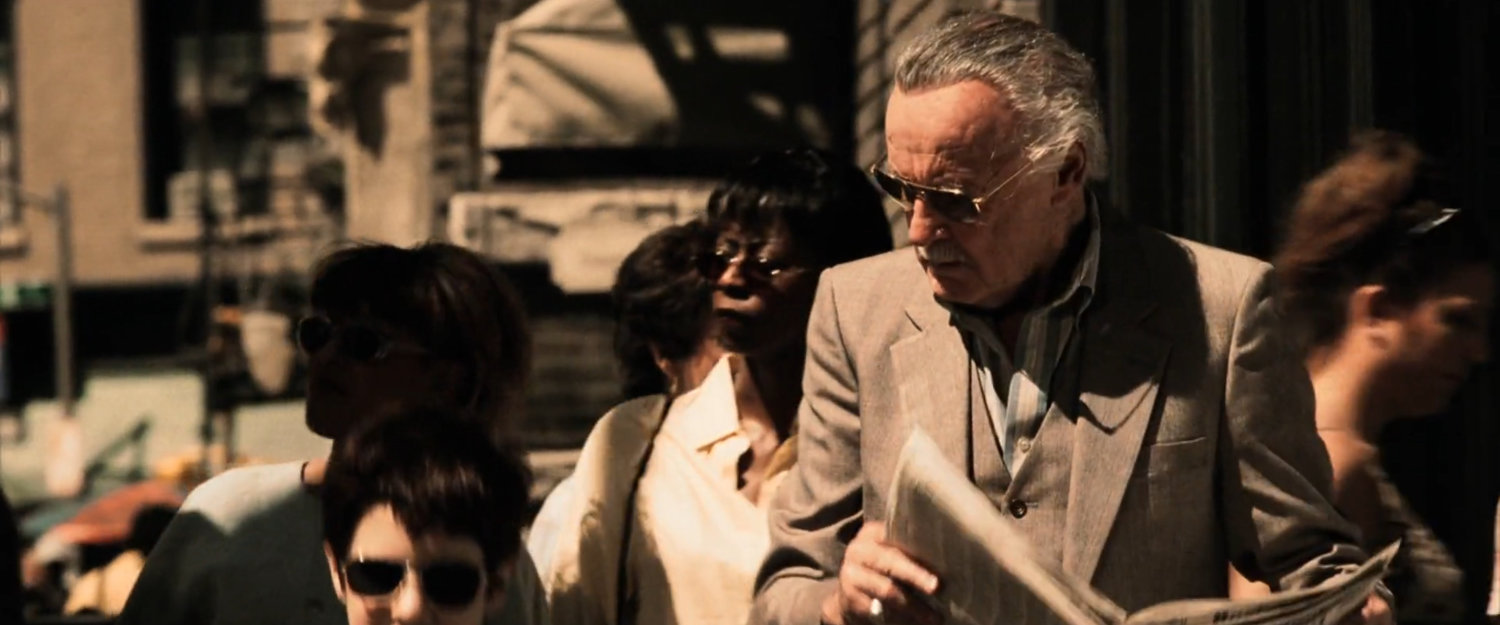 Young Matt next to Stan Lee on sidewalk corner.