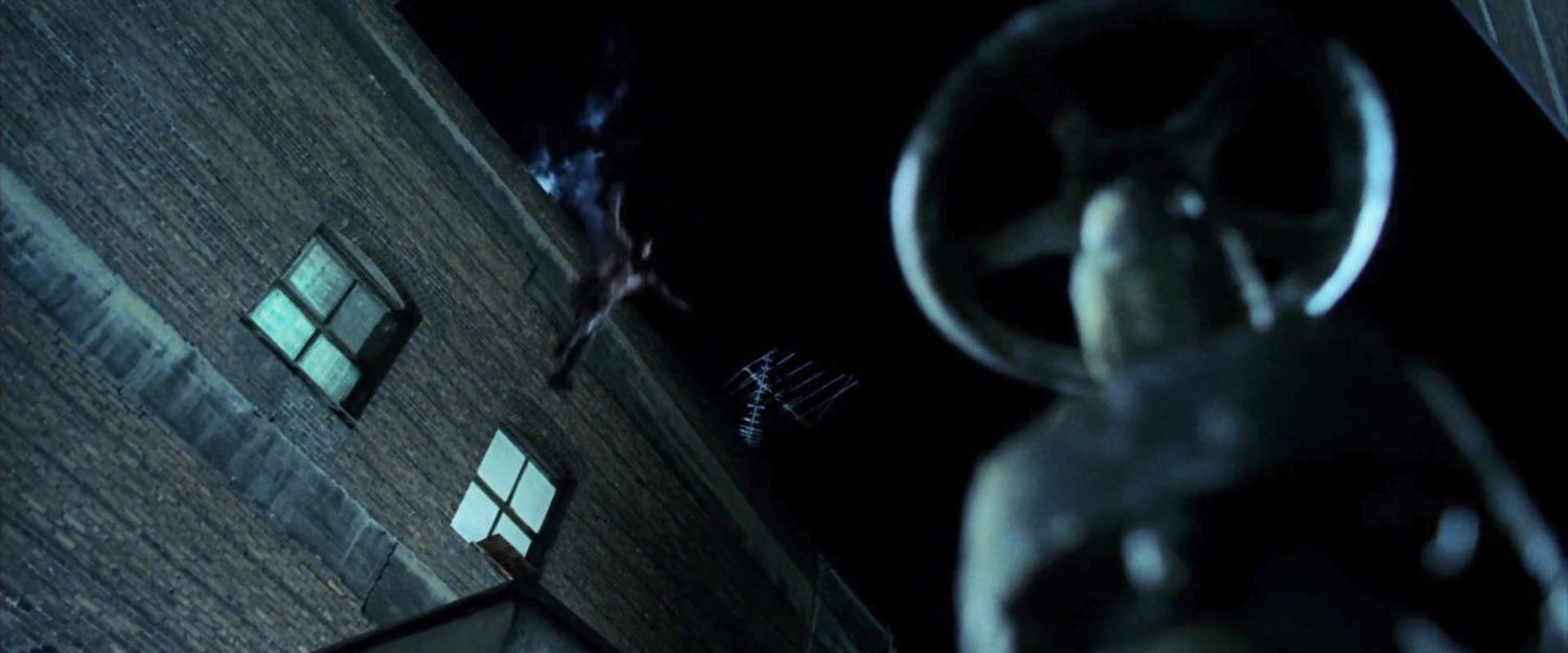 Daredevil leaping over rooftop ledge at night.