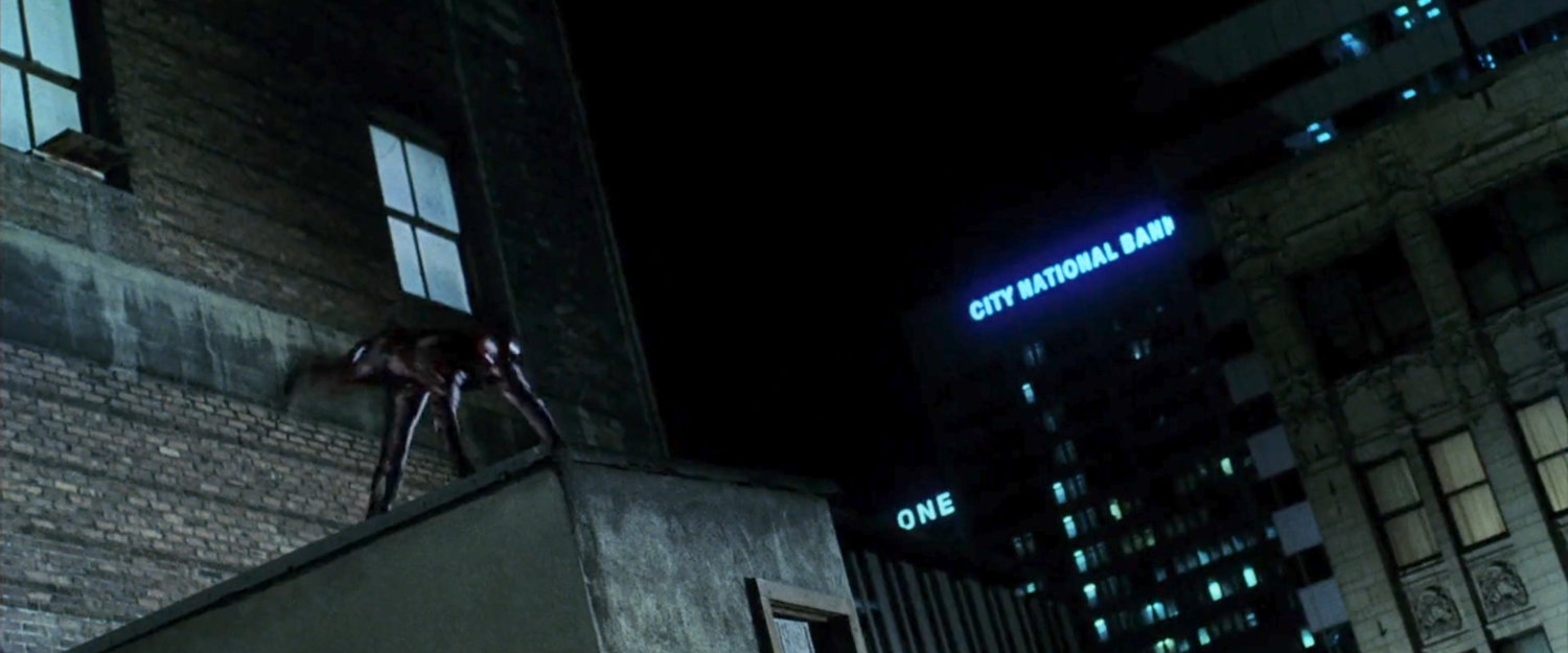Daredevil somersaulting over rooftop ledge at night.