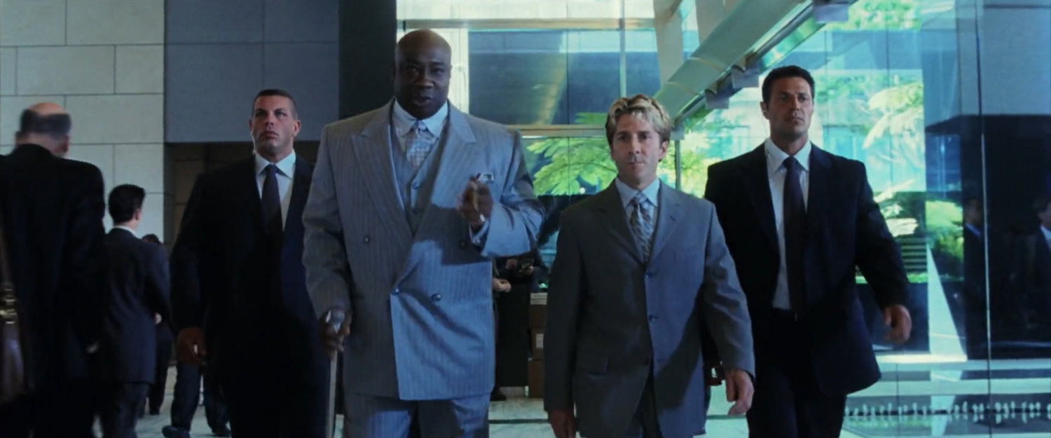 Fisk and Wesley with two bodyguards walk through the lobby at Fisk Corp.