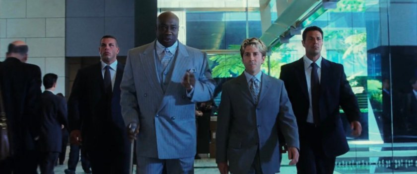Fisk and Wesley with two bodyguards walk through the lobby at Fisk Corp.