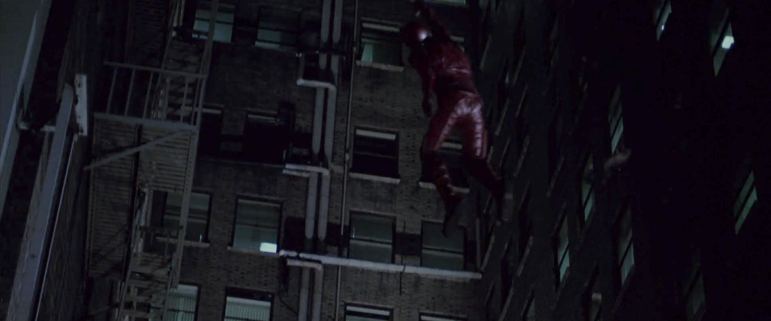 Daredevil escaping up the side of an apartment building.