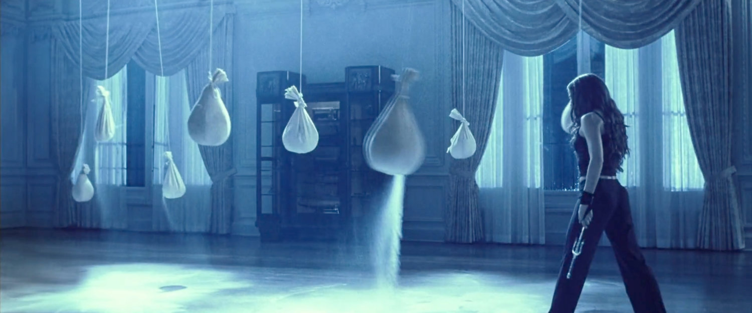 Elektra standing by sandbags after training in her mansion.