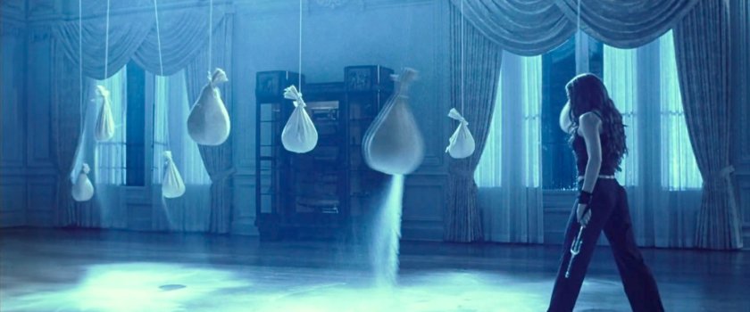 Elektra standing by sandbags after training in her mansion.