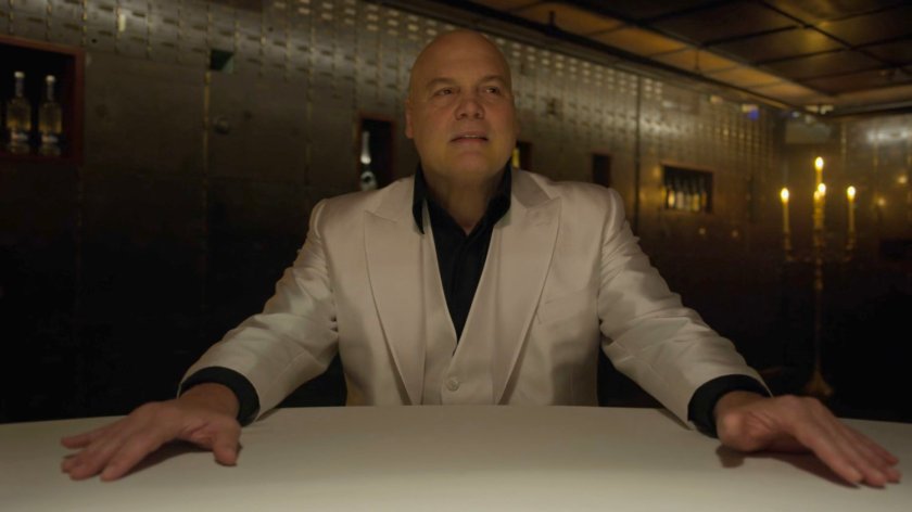 Kingpin sitting at a table in the Red Fish Blue Restaurant.