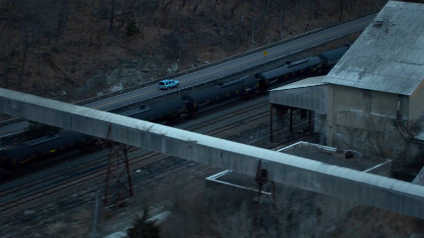 Karen's blue truck driving on a road along side a train track in Vermont.