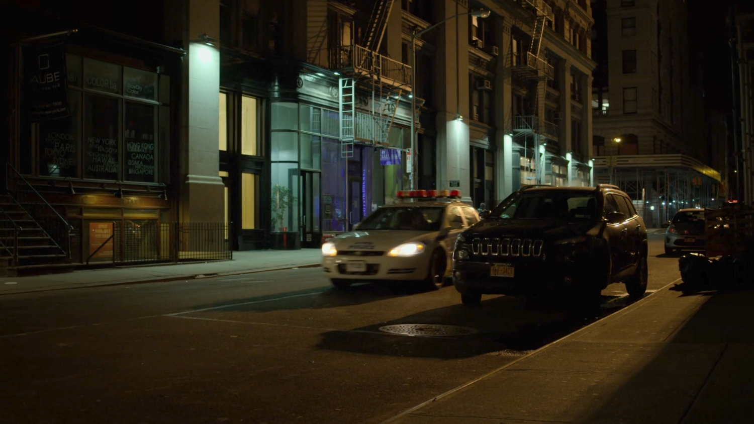 A police car pulls up along a dark street.