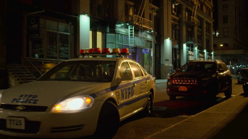 A police car pulls up along a dark street.