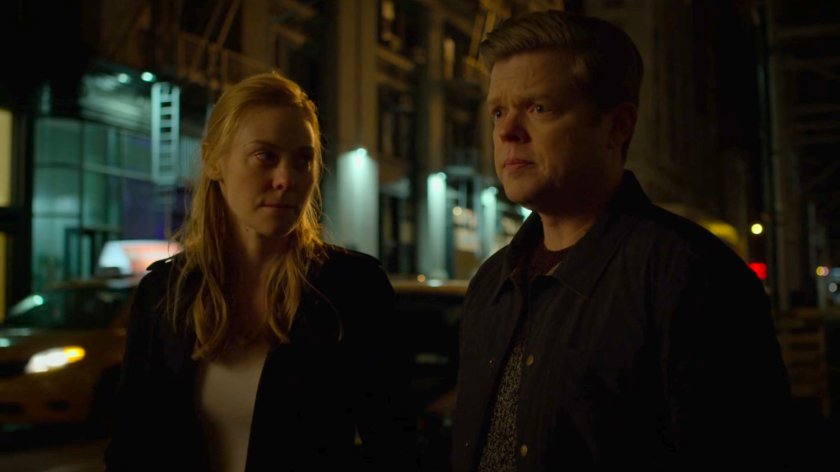 Karen and Foggy on a dark sidewalk by a squad car.