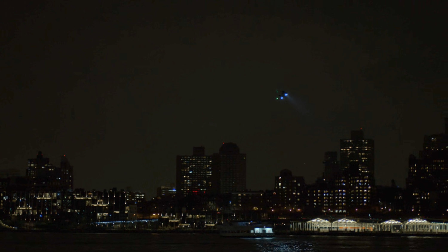 Helicopter flying over East River at night.