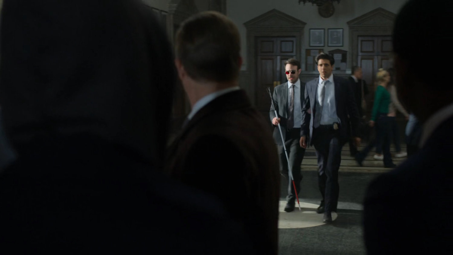 Matt and Nadeem walking towards Foggy in a courthouse.