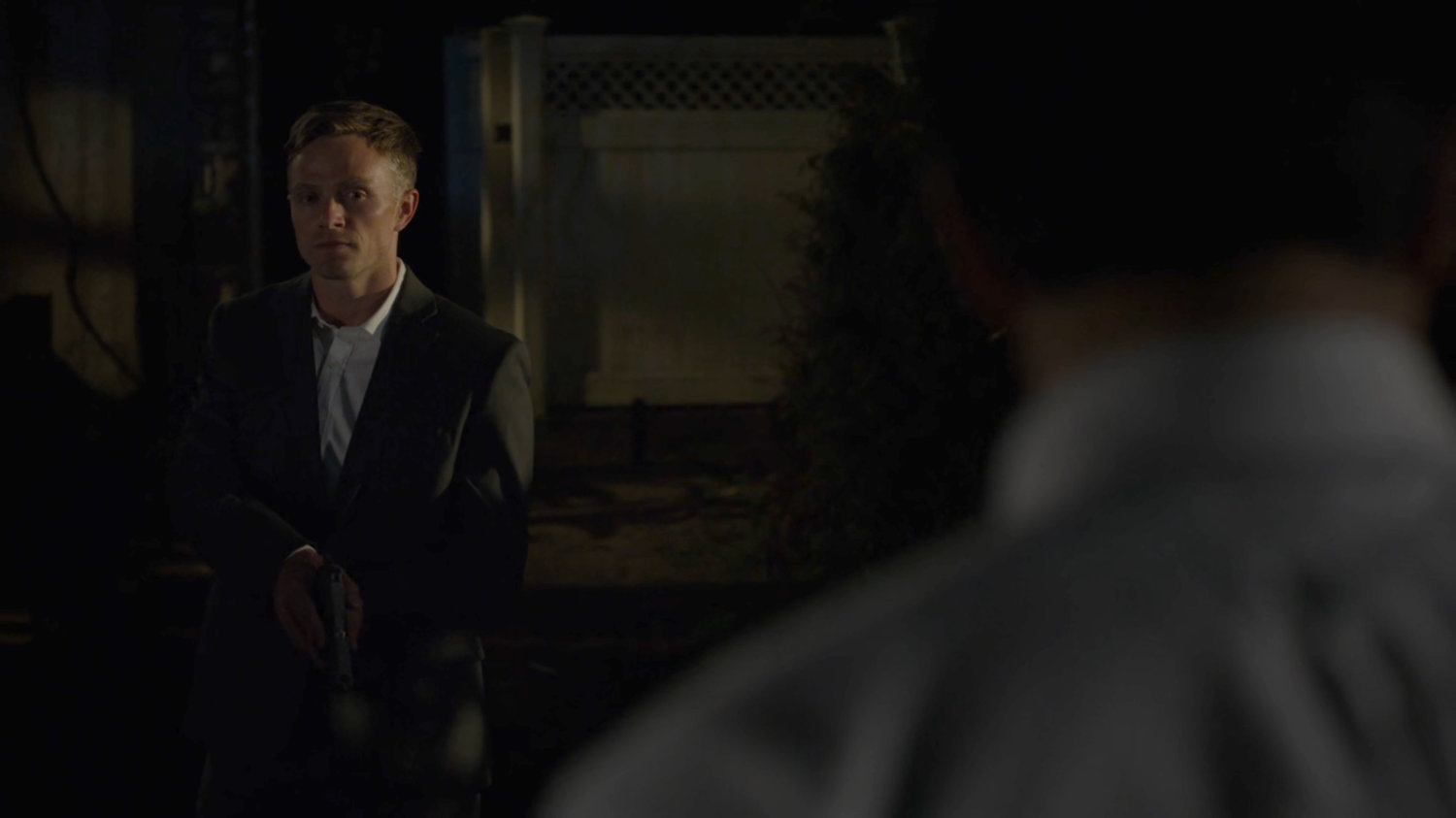 Dex holds a gun on Ray in the Nadeem backyard.