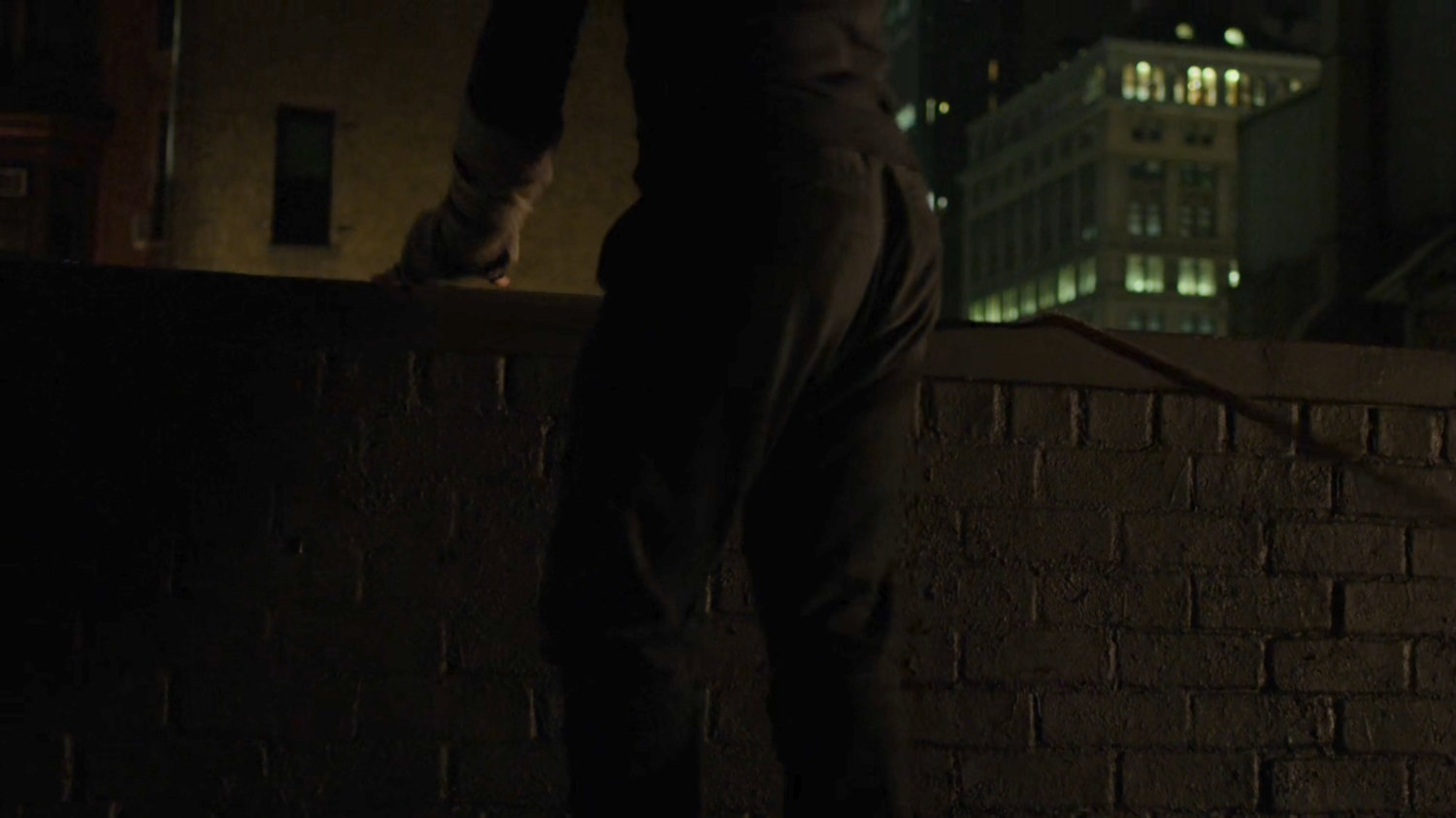 Matt standing by ledge on dark rooftop.