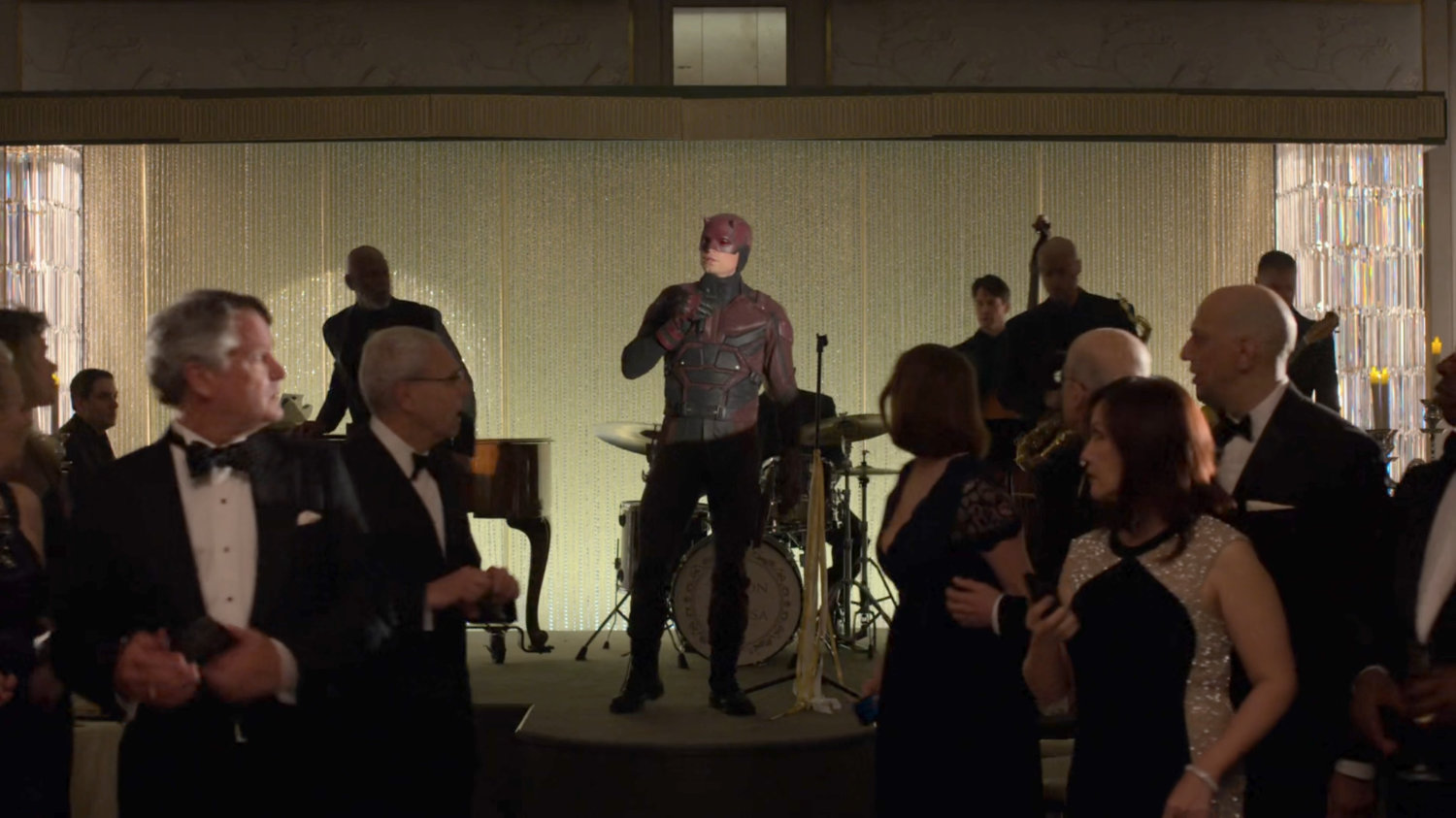 Dex, dressed as Daredevil, talks to the guests at the wedding reception in the Presidential Hotel ballroom.