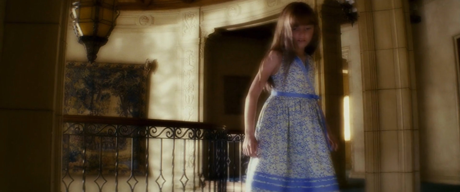 Young Elektra at the top of the stairs in the Natchios mansion.