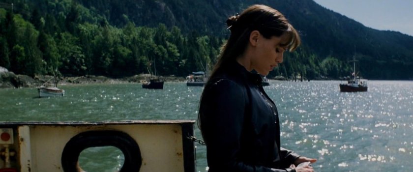 Elektra on a ferry with boats and mountains behind her.