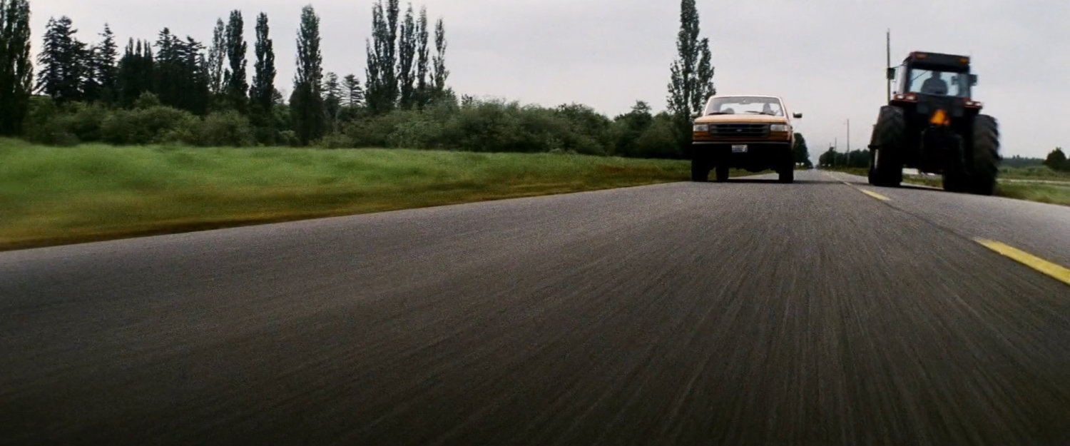 Pickup truck passing tractor on a rural road.