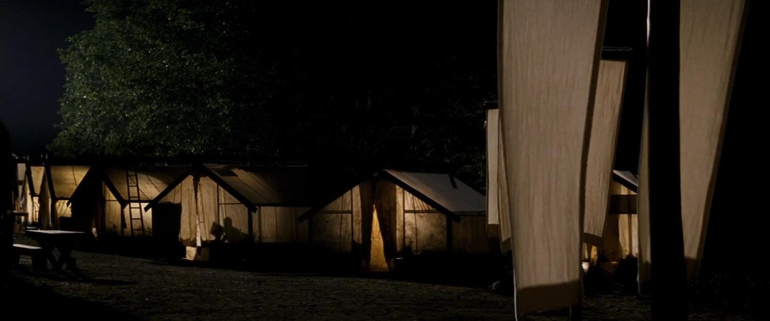 Cabins lit up at night in the Chaste camp.