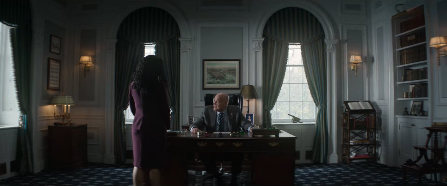 Fisk sitting at his desk in City Hall talking to Sheila.