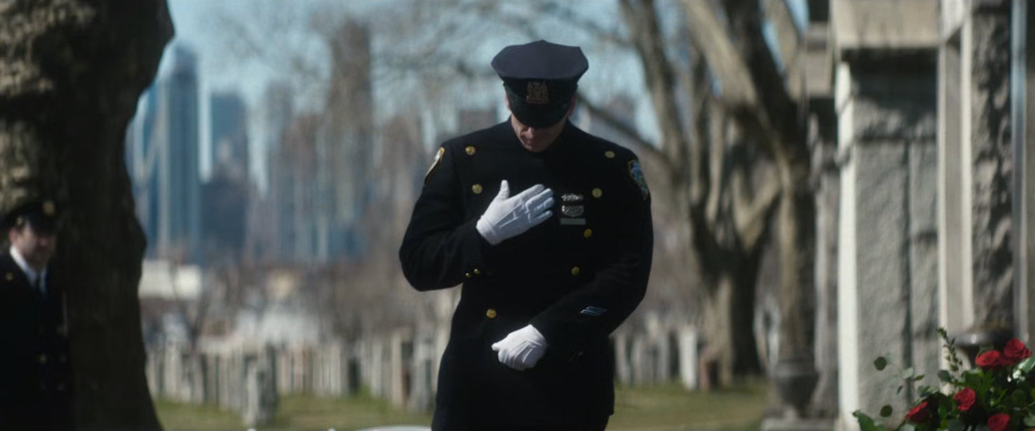 A Police officer salutes his fallen comrade.