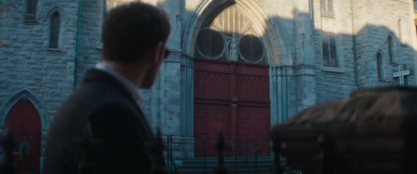 Matt standing across the street from a church with red doors.