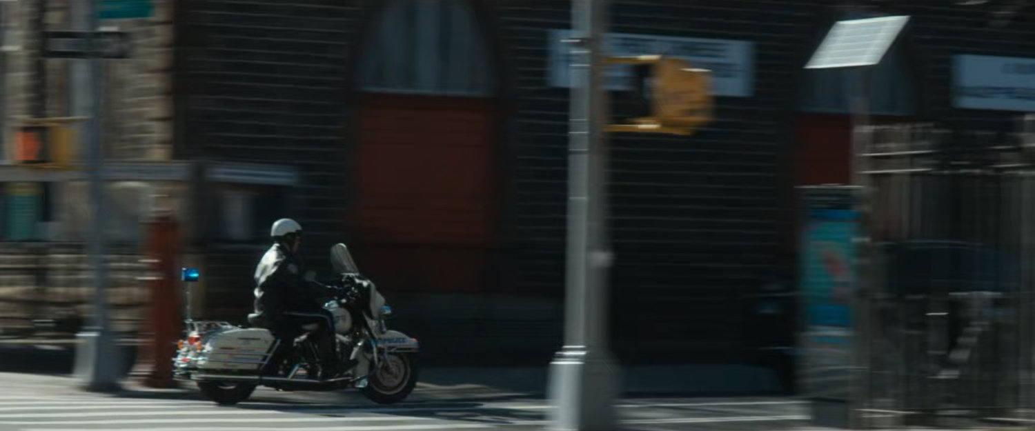 Motorcycle officer speeding past intersection.