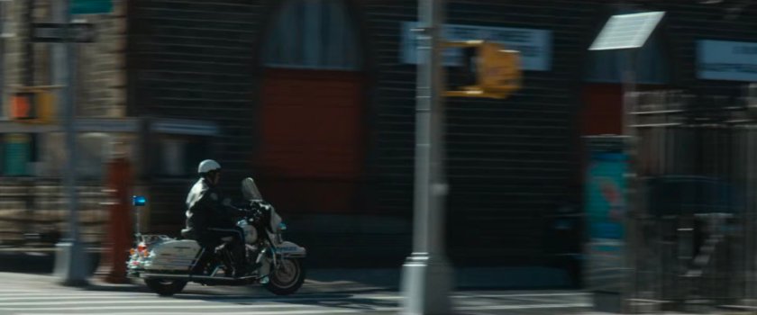 Motorcycle officer speeding past intersection.