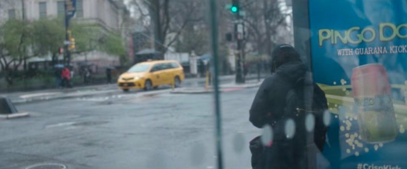 Interstitial: person sitting in bus stop by road.