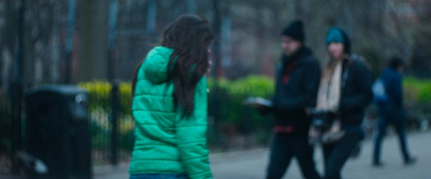 Interstitial: woman in green jacket near park.