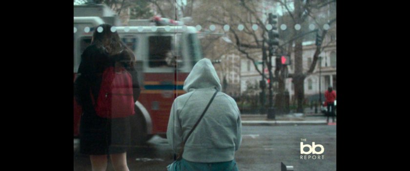 BB Report: person sitting in bus stop enclosure.