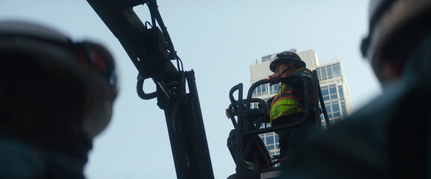 Sanitation worker on lift outside building.