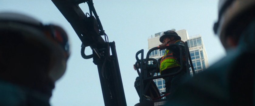 Sanitation worker on lift outside building.